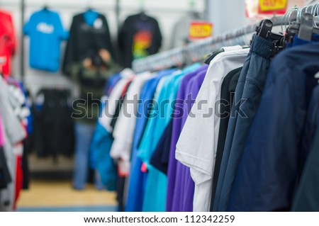 Bright color t-shirts and trousers on stands in supermarket