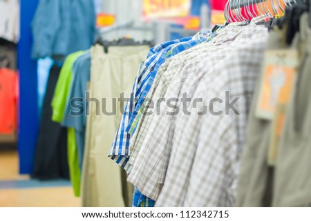 Variety of bright shirts and trousers on stands in supermarket