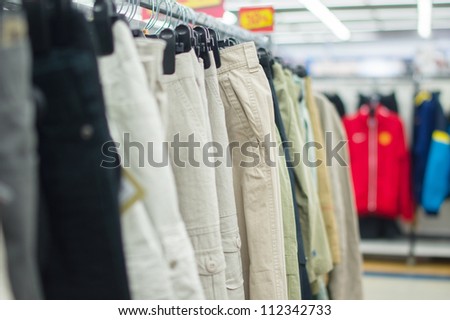 Variety of bright and dark trousers on stands in supermarket