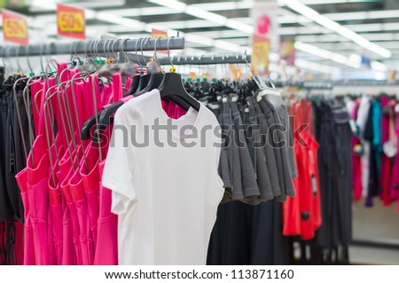 Bright t-shirts and shorts on stands in supermarket