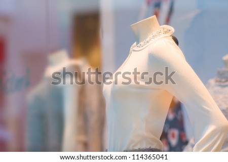 Color blouses on mannequins under shopping window in mall