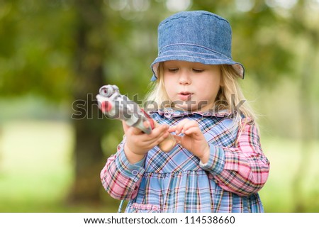 Adorable girl shoot with toy gun on playground