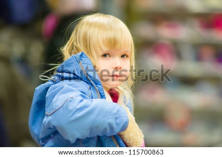 Adorable girl sit on shopping cart and selecting clothes