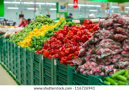 Bunch of red, green and yellow paprika pepper and radish on boxes in supermarket