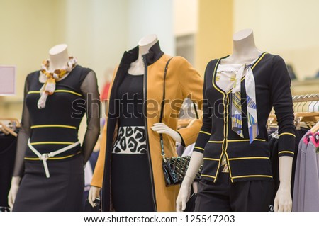 Three mannequins in dresses, skirts and jacket with bag in store
