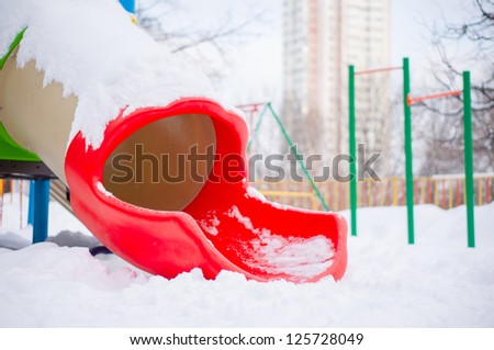 Kids tube slide on winter playground covered with snow