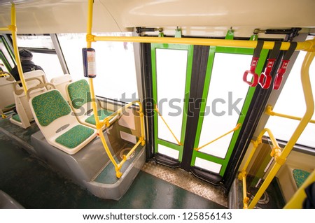 Interior of modern city bus. Seat places and door with handles on top in back side of bus. Wide angle shot