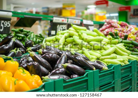 Bunch of eggplants and zucchini on boxes in supermarket