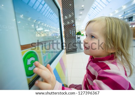 Adorable girl play computer game with touchscreen in supermarket