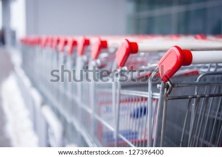 Rows of shopping carts on car park near entrance of supermarket
