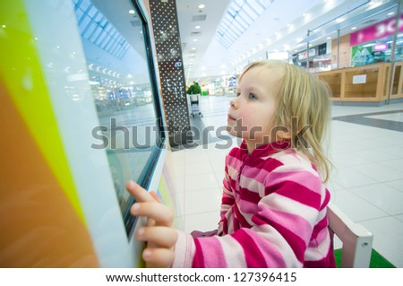 Adorable girl play computer game with touchscreen in supermarket