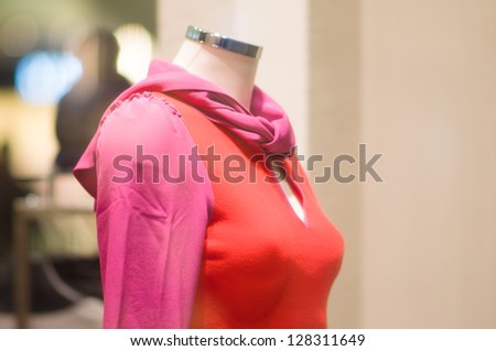 Red dress clothed mannequin under shopping window in store