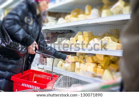 Customer select cheese pieces on shelves in supermarket