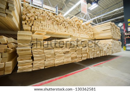 Lumber boards and beams of different sizes lie on racks and pallets in build supermarket