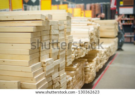 Lumber boards and beams of different sizes lie on racks and pallets in build supermarket