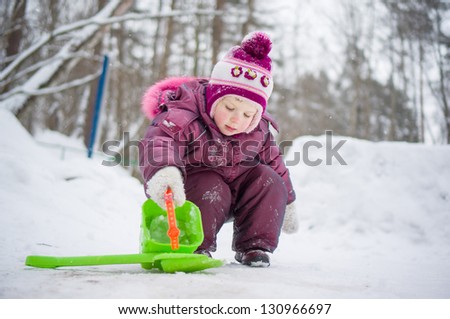 Adorable girl play with snow and water with small shovel and pail in park