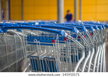 Rows of blue shopping carts on entrance of supermarket