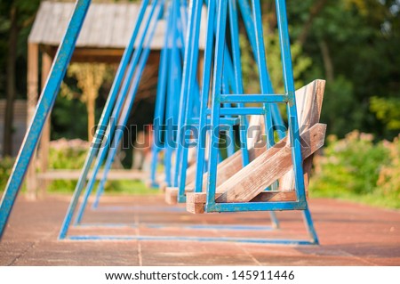 Blue metal swings with wood seats on kids playground