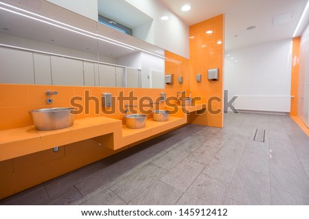 Modern City Public Toilet. Orange Wall With Sinks And Mirrors