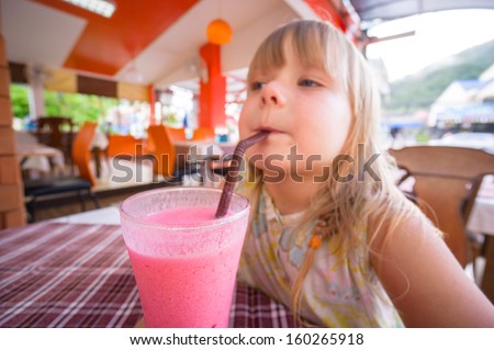 Adorable girl drink pink shake in restaurant