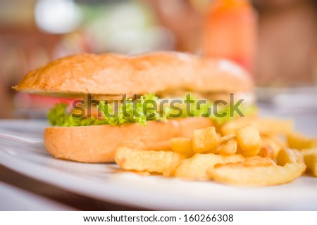Sandwich with chicken and french fries on plate in beach restaurant