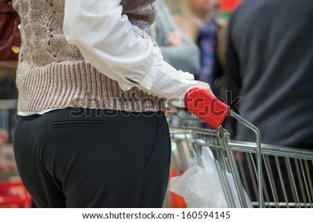 Customer with trolley in queue near cash desk in supermarket