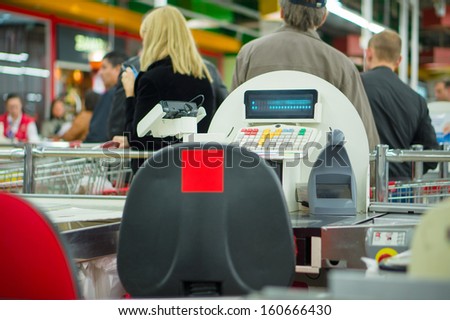 Empty Cash Desk And Queue Of Customers On Back In Supermarket