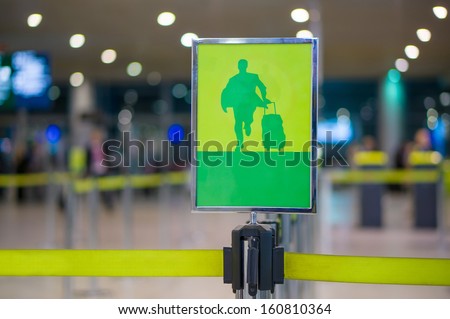 Exit sign - Man with luggage on waiting line at check in desk in airport