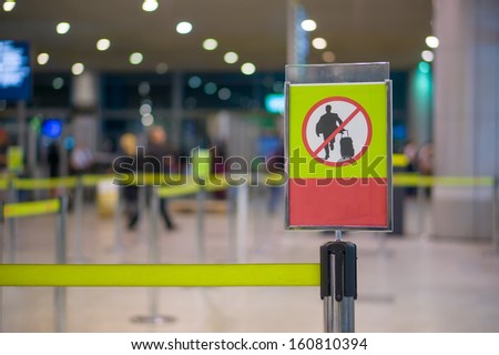 No entry sign - Man with luggage on waiting line at check in desk in airport