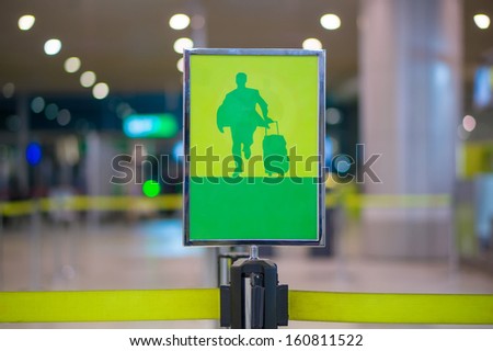 Exit sign - Man with luggage on waiting line at check in desk in airport