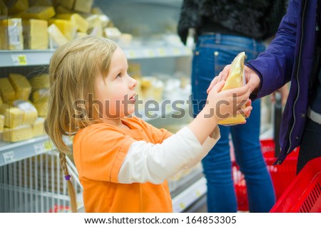 Adorable girl select cheese with mother in supermarket