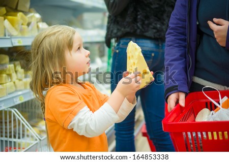 Adorable girl select cheese with mother in supermarket