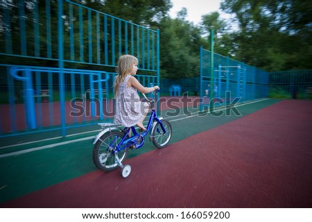 Adorable girl ride on bike with training wheels on playground