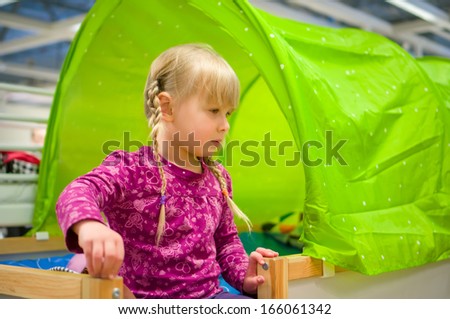 Adorable girl sit on loft bed in furniture shop