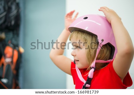 Adorable girl fitting bike helmet in sport store