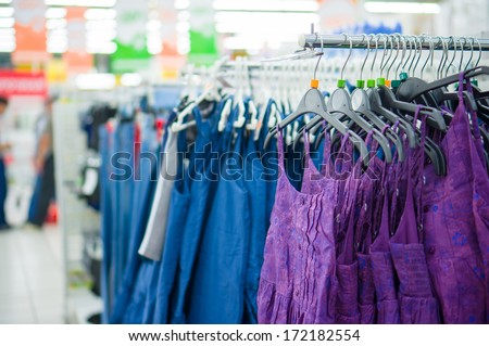 Dresses on curved hangers on bars in supermarket