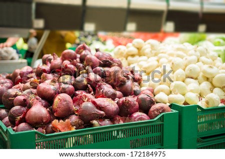 Bunch of red and silver onions on boxes in supermarket