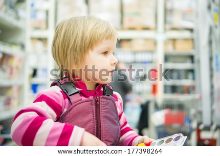 Adorable girl sit on shopping cart  in supermarket