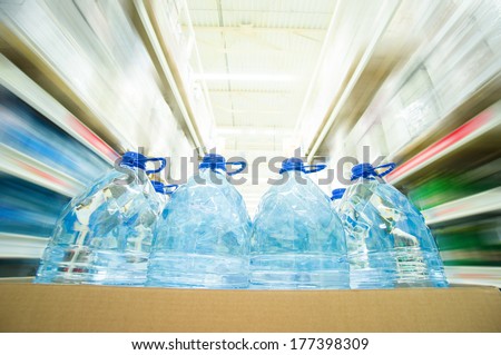 Blue bottles with water in cardboard box in supermarket. Wide angle shot