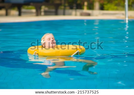 Beautiful young woman relax on life ring in pool in tropical beach resort