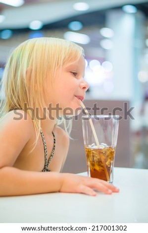 Adorable girl have meal with soda drink and fried potatoes at fast food restaurant