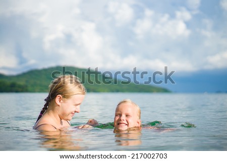 Young mother and daughter have fun swim on island in tropical ocean