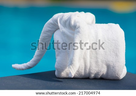 Towels in form of elephants on sunbed at luxury swimming pool