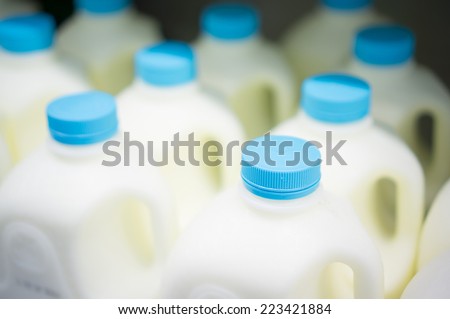 Bunch of milk bottles on fridge shelf in supermarket