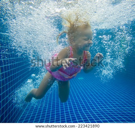 Adorable girl swim underwater after jumping into pool
