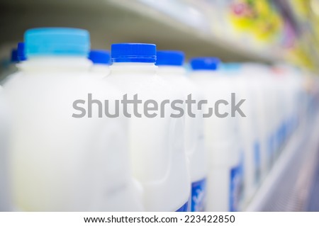 Bunch of milk bottles on fridge shelf in supermarket