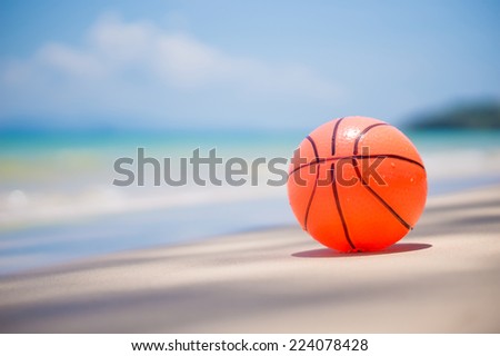 Orange ball on sand beach near ocean with waves