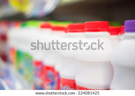 Bunch of milk products bottles on fridge shelf in supermarket