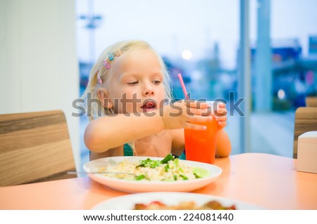 Adorable girl dinning on food court with vegetables rice and juicy drink with straw