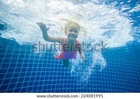 Adorable girl swim underwater after jumping into pool